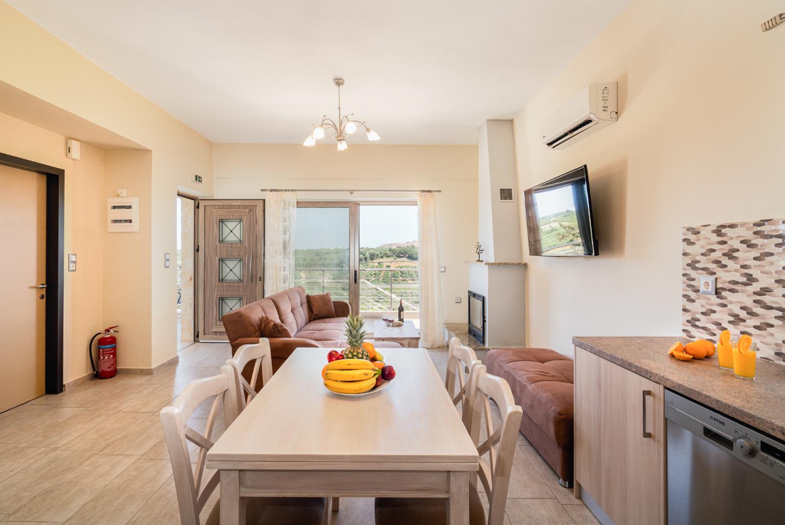 Open-plan living room with sofas, dining area, kitchen, ornamental fireplace, A/C, WiFi internet, and satellite TV