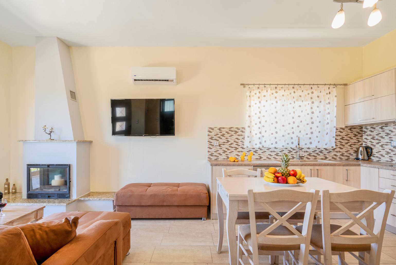 Open-plan living room with sofas, dining area, kitchen, ornamental fireplace, A/C, WiFi internet, and satellite TV