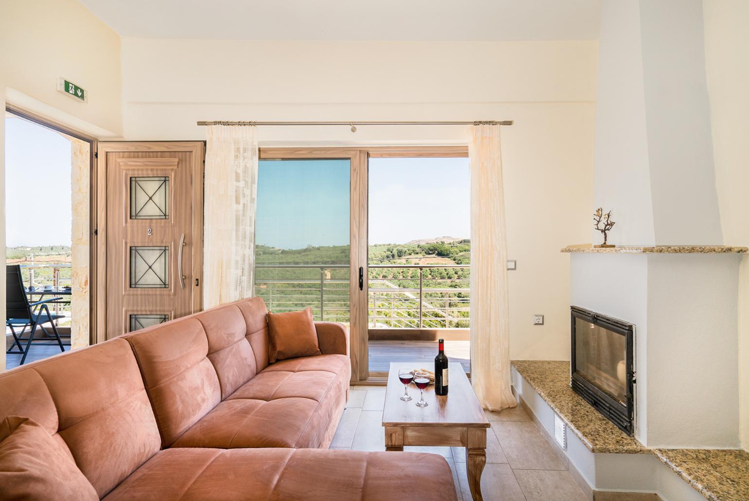 Open-plan living room with sofas, dining area, kitchen, ornamental fireplace, A/C, WiFi internet, and satellite TV