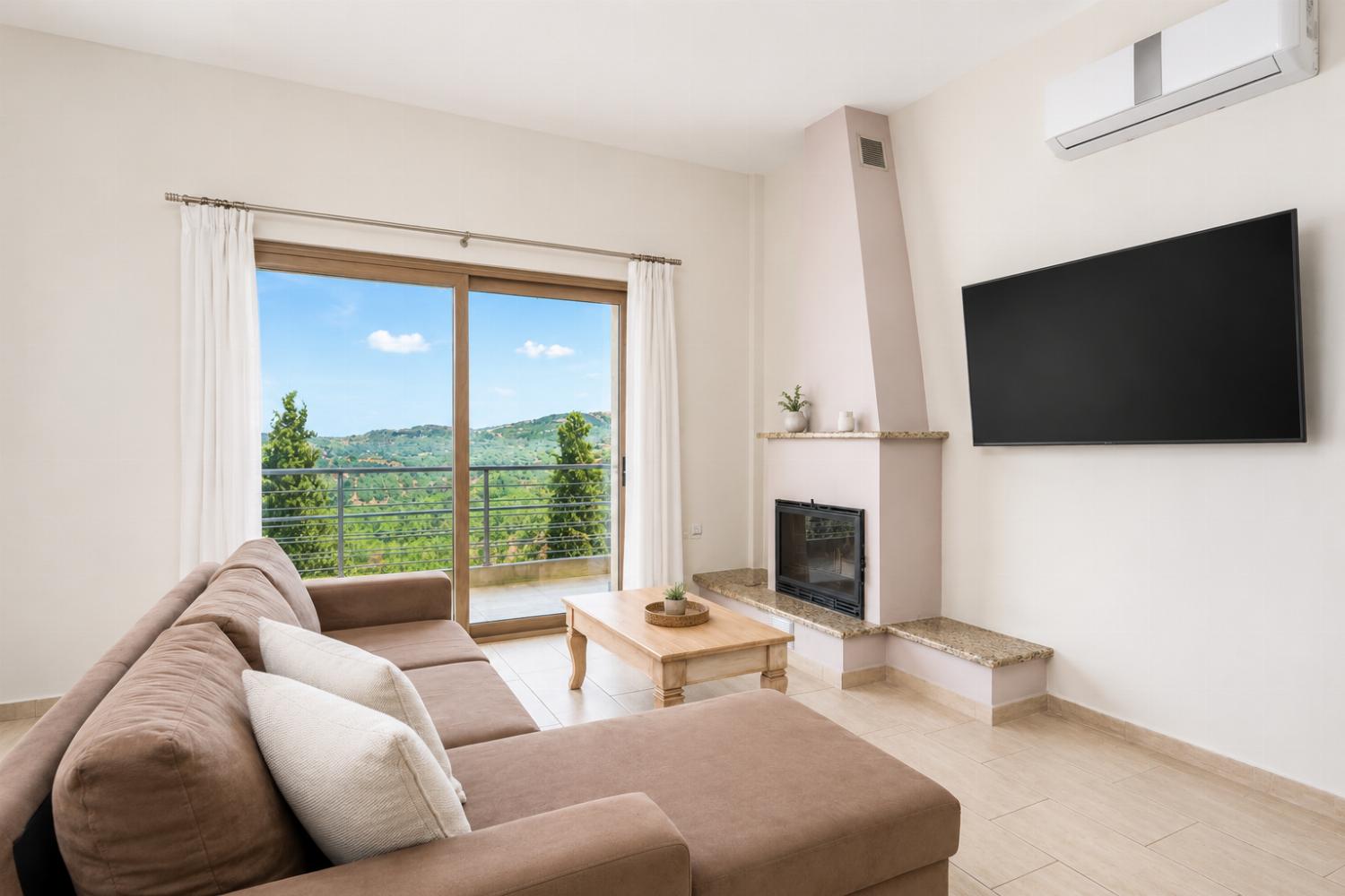 Open-plan living room with sofa, dining area, kitchen, ornamental fireplace, A/C, WiFi internet, and satellite TV