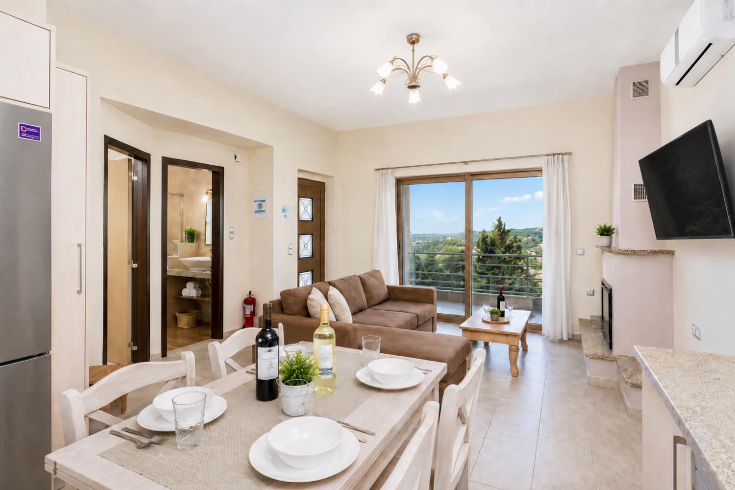 Open-plan living room with sofa, dining area, kitchen, ornamental fireplace, A/C, WiFi internet, and satellite TV
