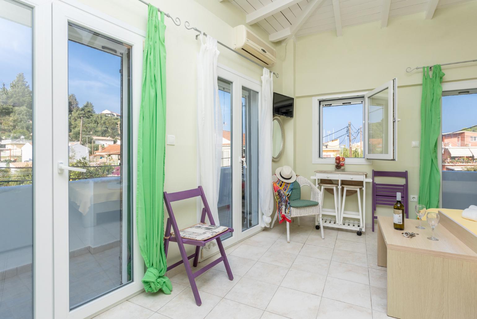 Open-plan living room with sofas, dining area, kitchen, A/C, WiFi internet, satellite TV, and balcony access