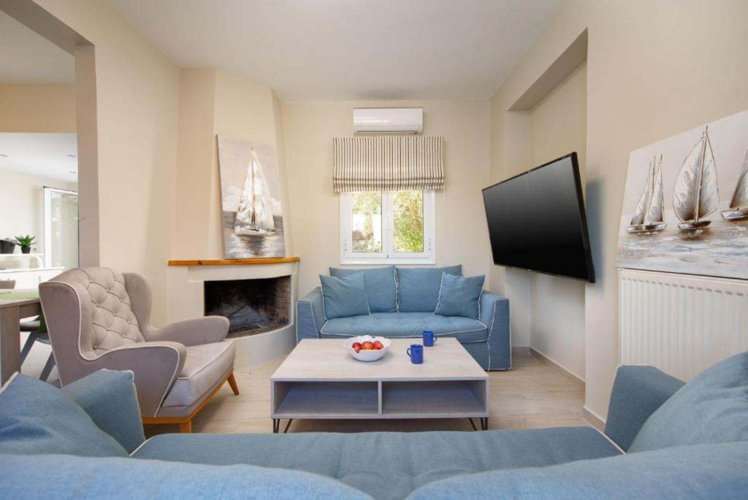 Living room with comfortable sofas, TV, A/C and ornamental fireplace