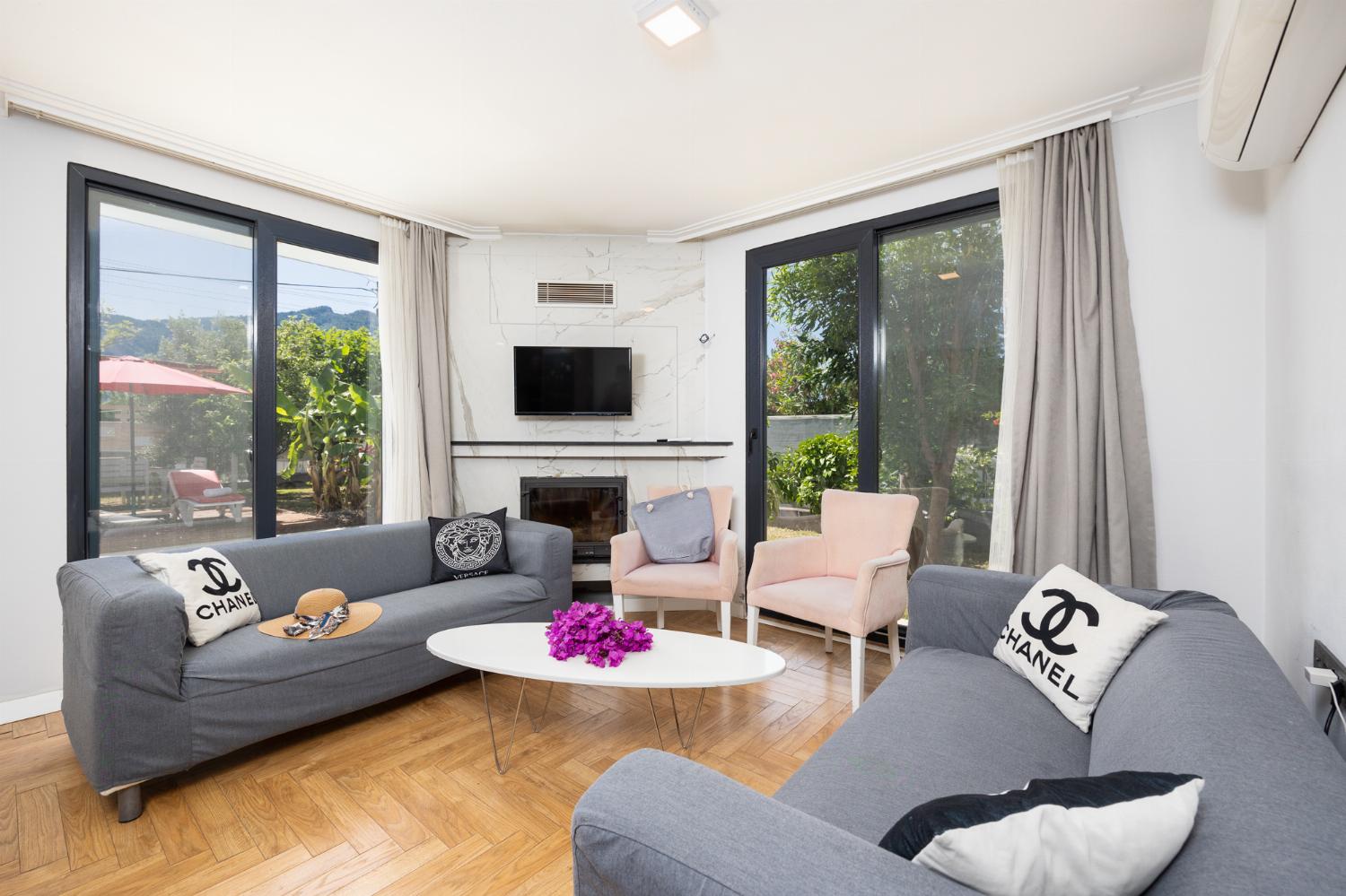Open-plan living room with sofas, dining area, kitchen, ornamental fireplace, A/C, WiFi Internet, and satellite TV
