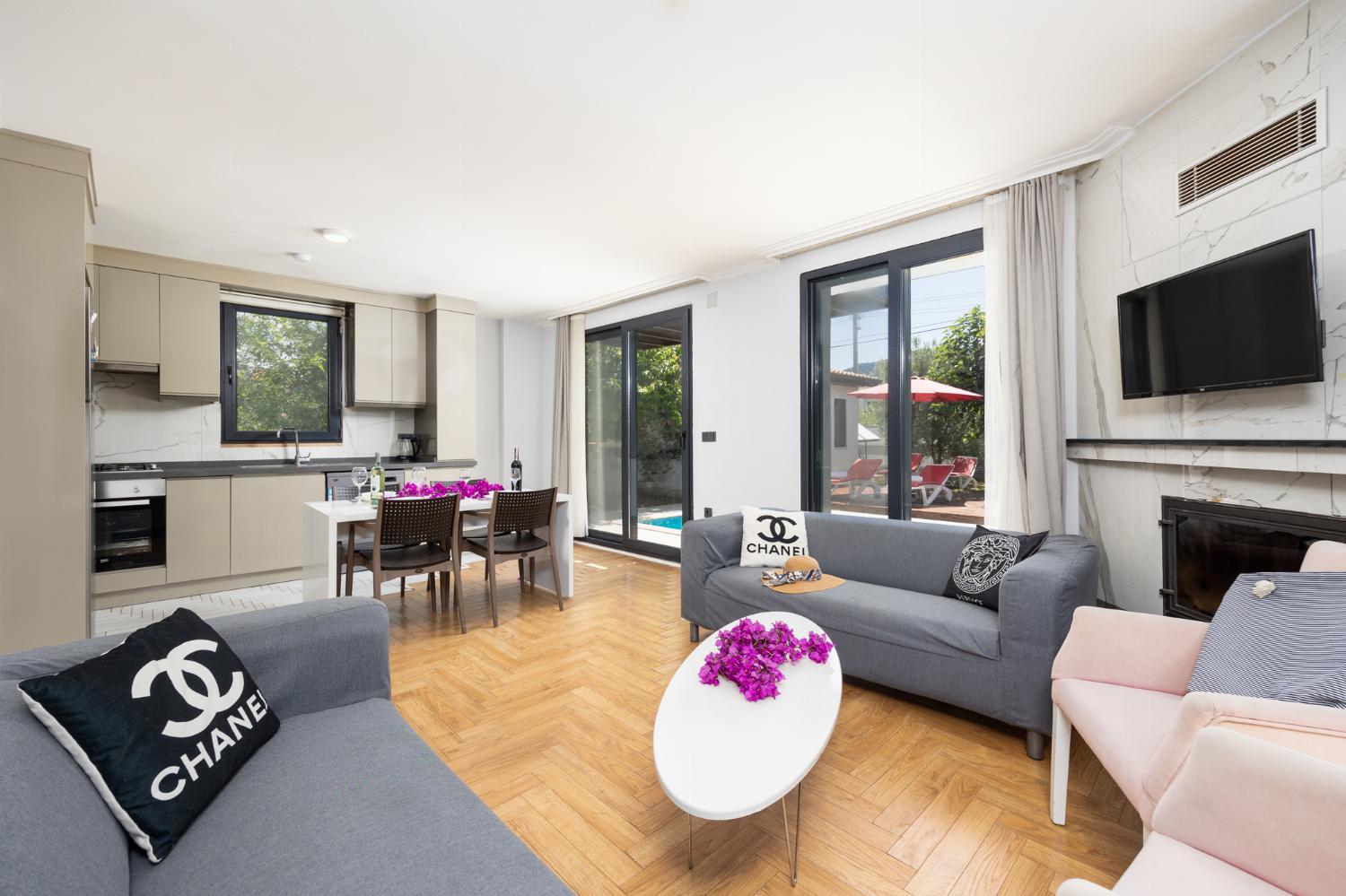 Open-plan living room with sofas, dining area, kitchen, ornamental fireplace, A/C, WiFi Internet, and satellite TV