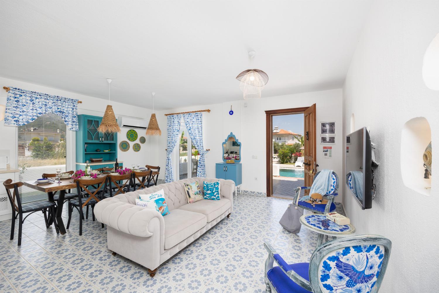 Open-plan living room with sofa, dining area, kitchen, A/C, WiFi internet, and satellite TV