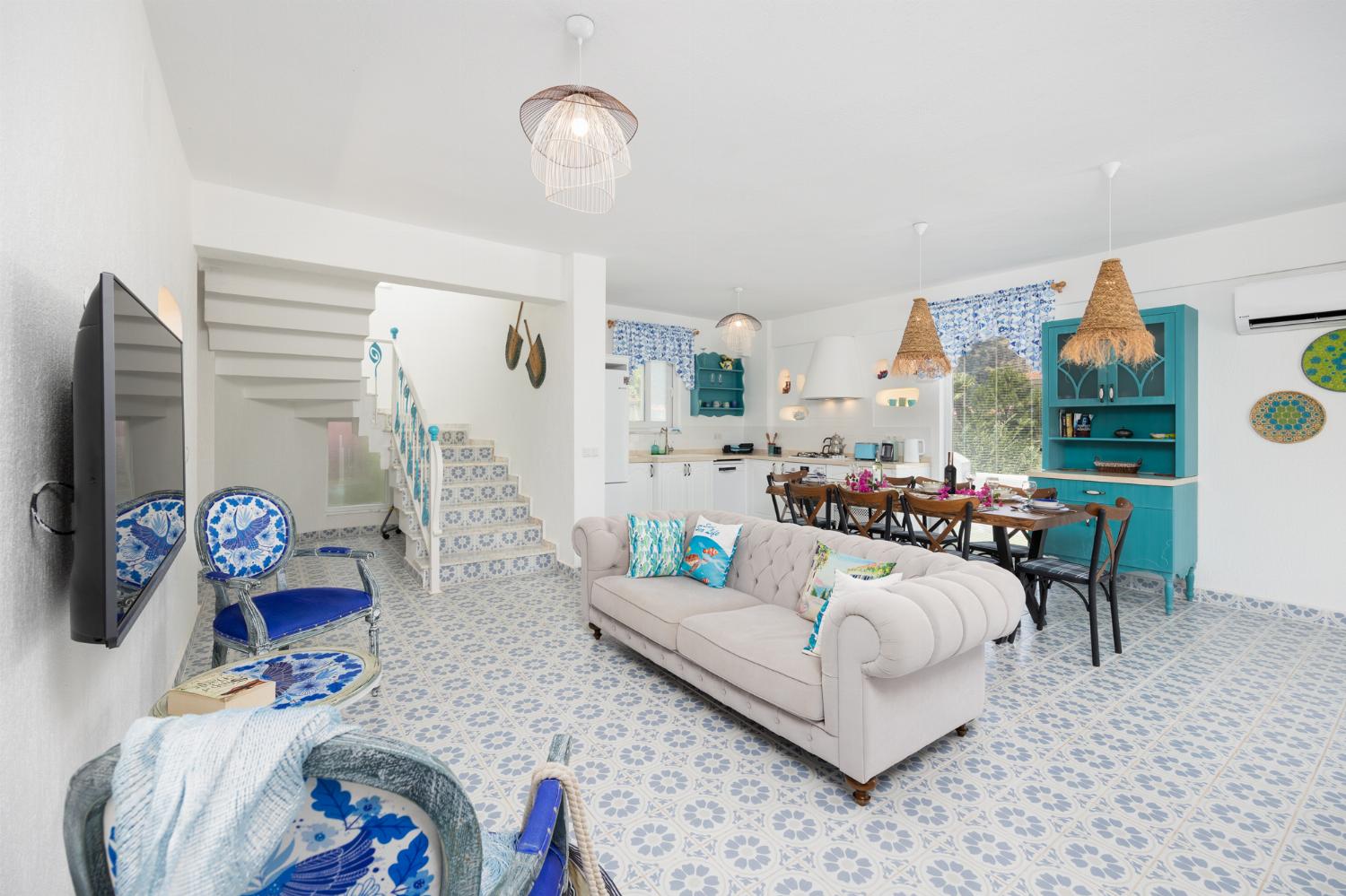 Open-plan living room with sofa, dining area, kitchen, A/C, WiFi internet, and satellite TV