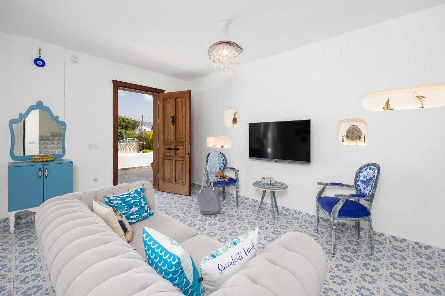 Open-plan living room with sofa, dining area, kitchen, A/C, WiFi internet, and satellite TV