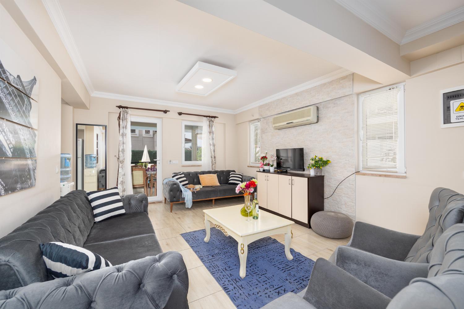 Open-plan living room with sofas, kitchen, A/C, WiFi internet, and satellite TV