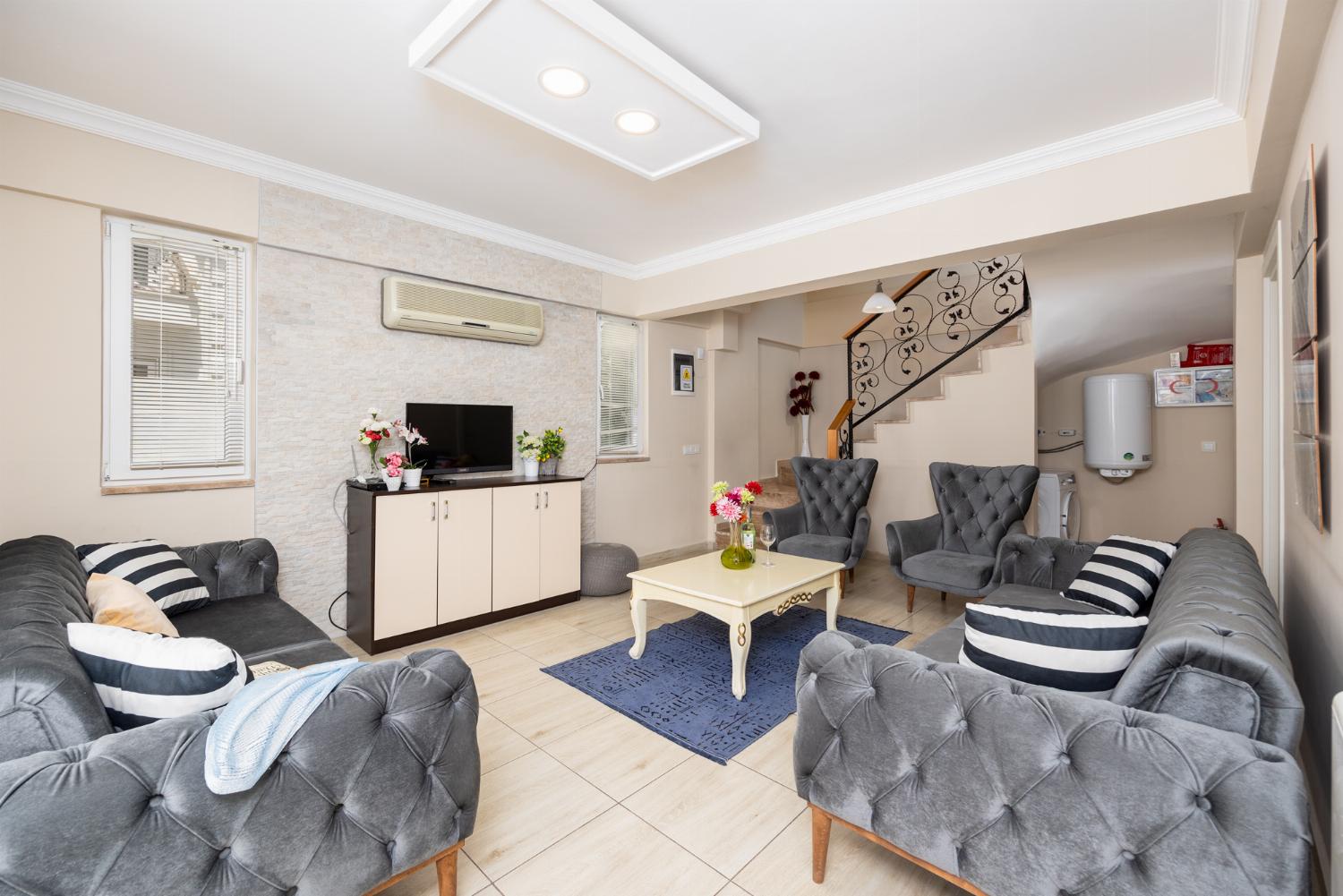 Open-plan living room with sofas, kitchen, A/C, WiFi internet, and satellite TV