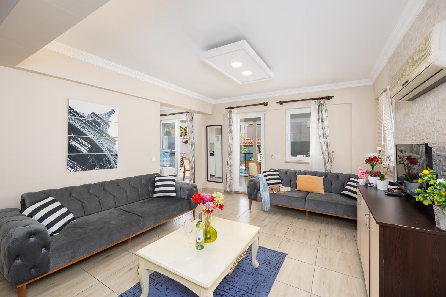 Open-plan living room with sofas, kitchen, A/C, WiFi internet, and satellite TV