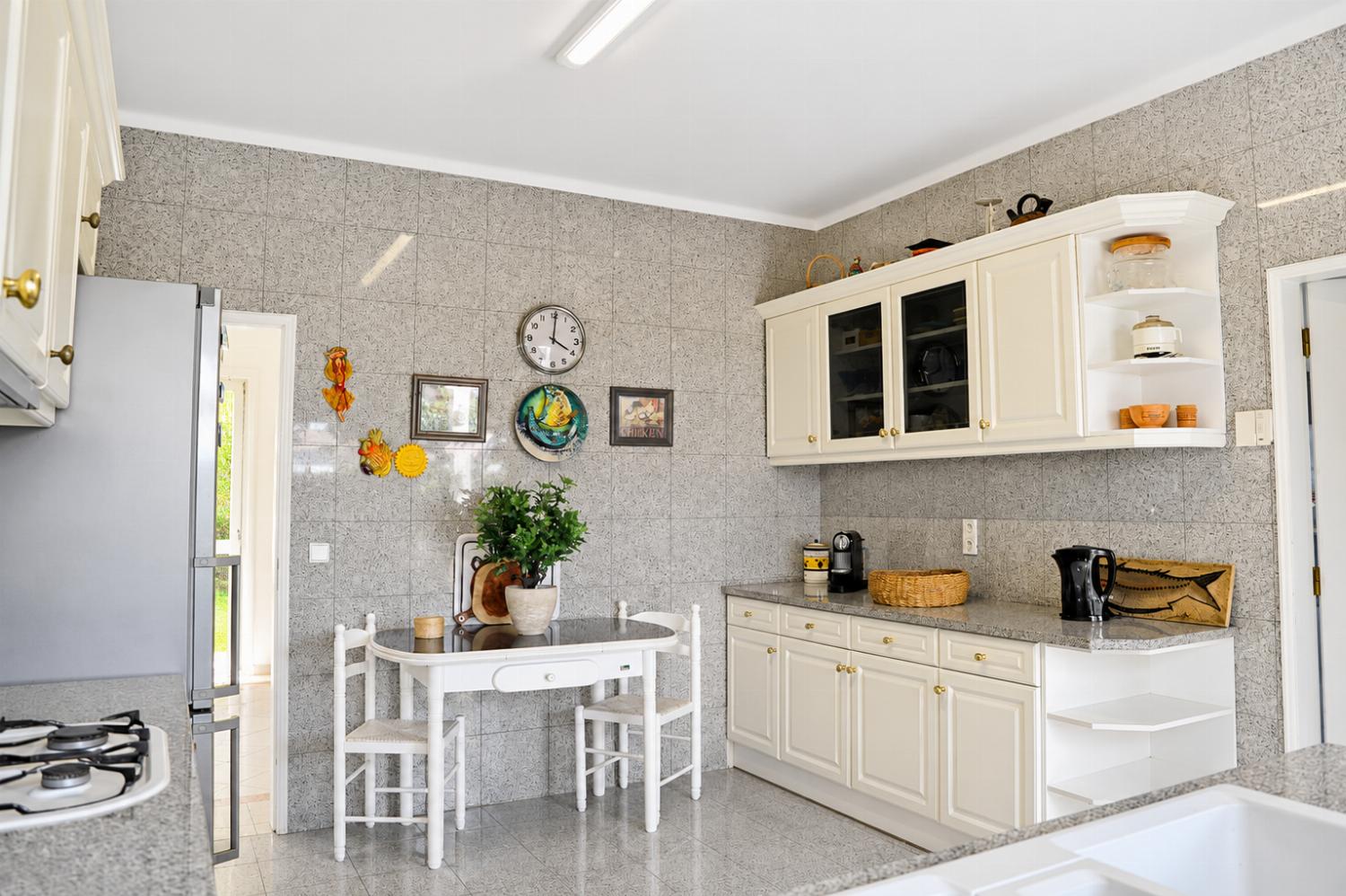 Bright kitchen with white cabinetry, granite tile walls, and a small dining table set.
