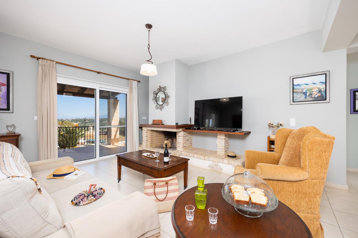 Open-plan living room with sofa, dining area, kitchen, ornamental fireplace, A/C, WiFi internet, and satellite TV