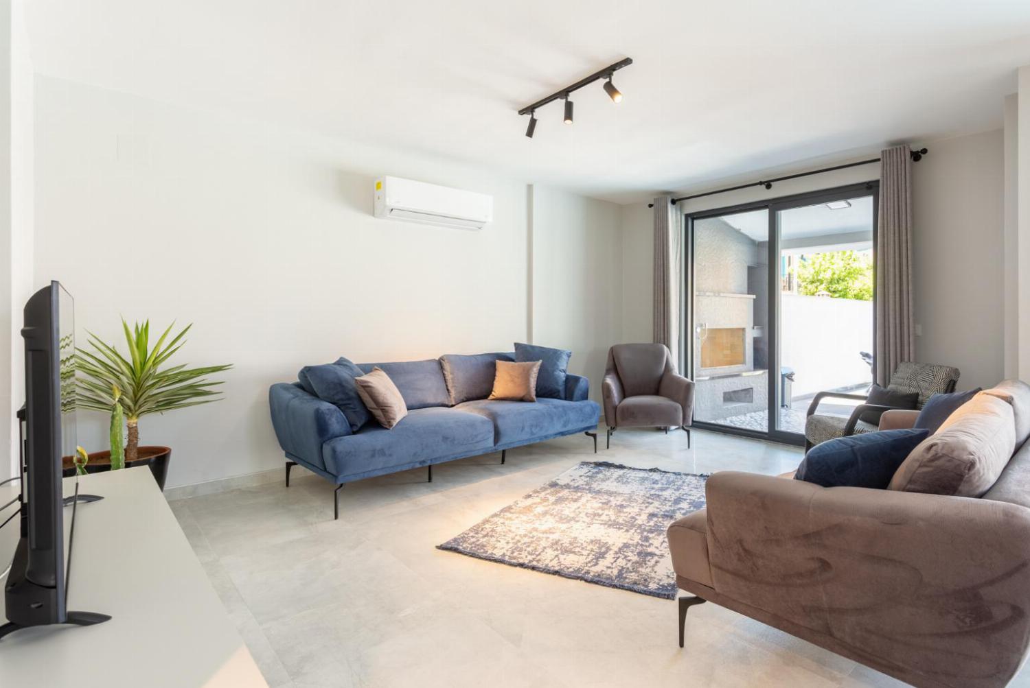 Open plan living room with confortable sofas, TV, and A/C