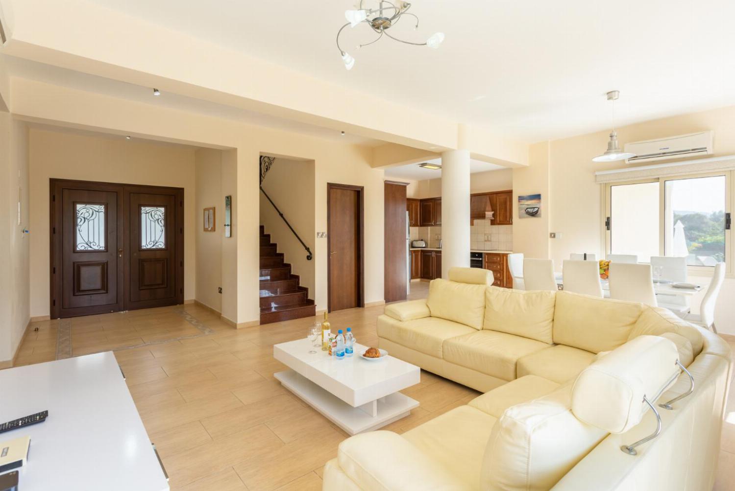 Open-plan living room with sofas, dining area, kitchen, ornamental fireplace, A/C, WiFi internet, and satellite TV