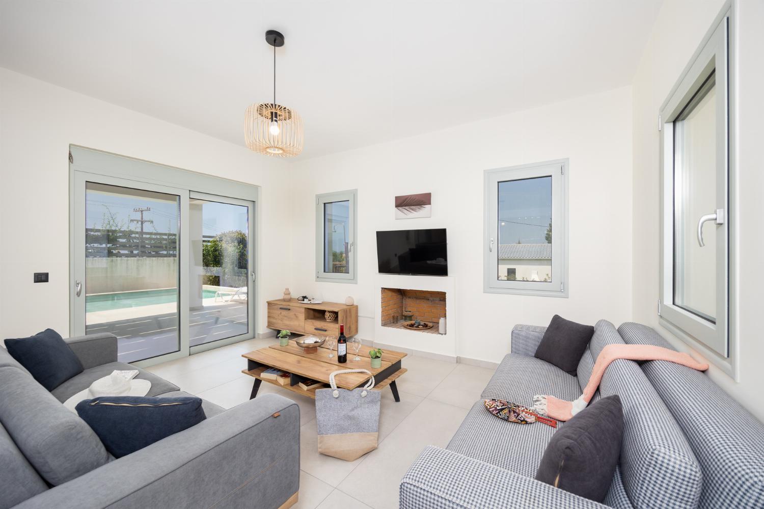 Open-plan living room with sofas, dining area, kitchen, ornamental fireplace, A/C, WiFi internet, and satellite TV