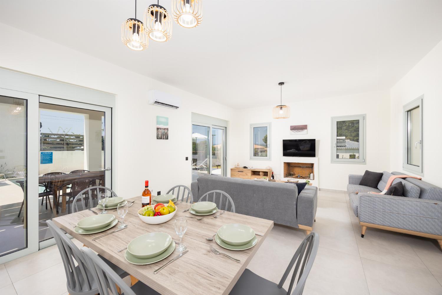 Open-plan living room with sofas, dining area, kitchen, ornamental fireplace, A/C, WiFi internet, and satellite TV