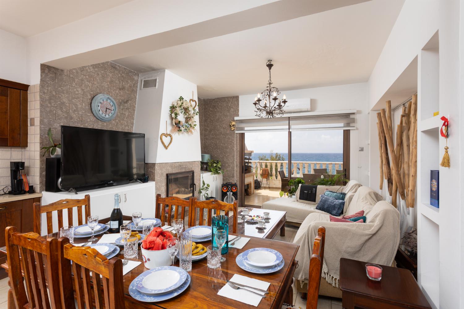 Main building: open-plan living room with sofas, dining area, kitchen, ornamental fireplace, A/C, WiFi internet, satellite TV, and sea views