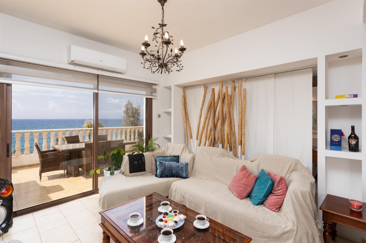 Main building: open-plan living room with sofas, dining area, kitchen, ornamental fireplace, A/C, WiFi internet, satellite TV, and sea views