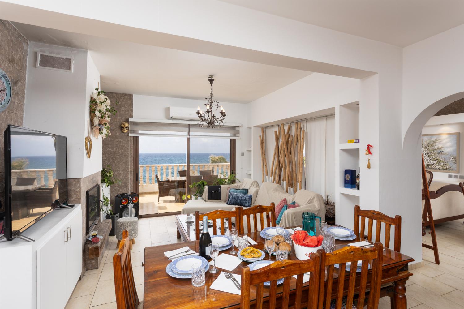 Main building: open-plan living room with sofas, dining area, kitchen, ornamental fireplace, A/C, WiFi internet, satellite TV, and sea views