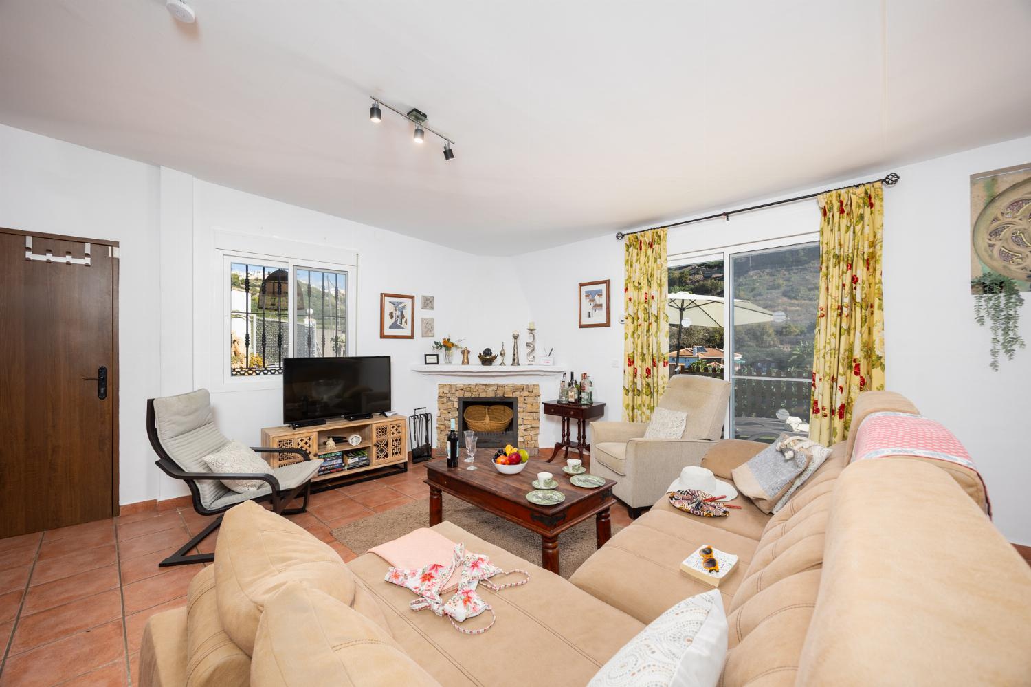 Open-plan living room with sofa, dining area, kitchen, ornamental fireplace, A/C, WiFi internet, and satellite TV