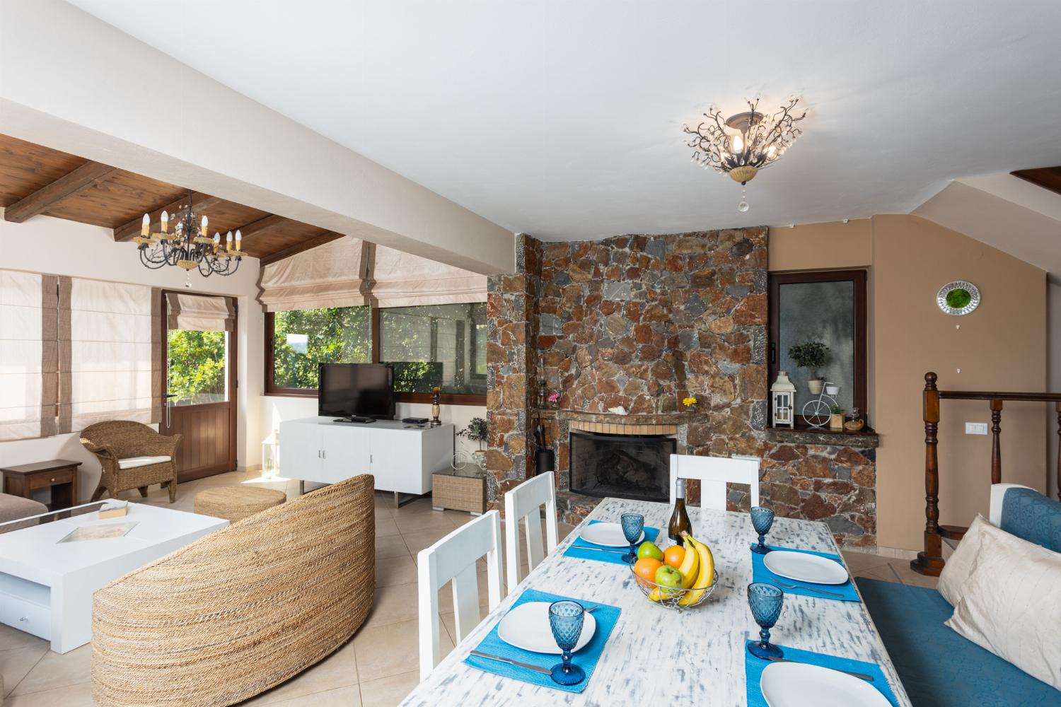 Open-plan living room with sofas, dining area, kitchen, mezzanine, ornamental fireplace, A/C, WiFi internet, and satellite TV