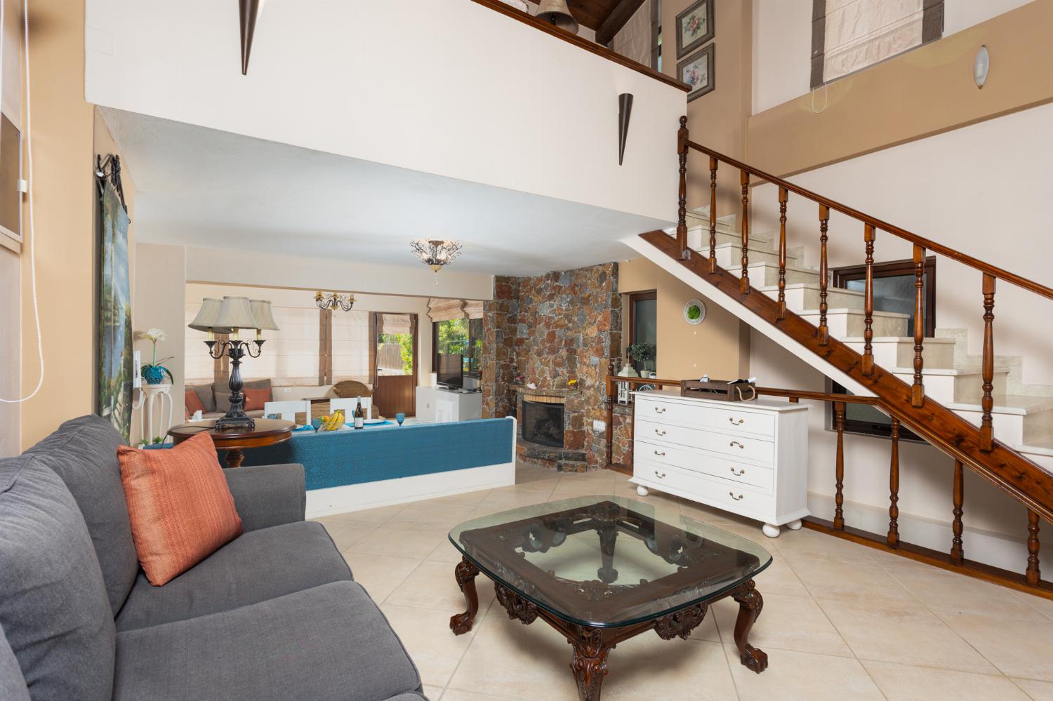Open-plan living room with sofas, dining area, kitchen, mezzanine, ornamental fireplace, A/C, WiFi internet, and satellite TV