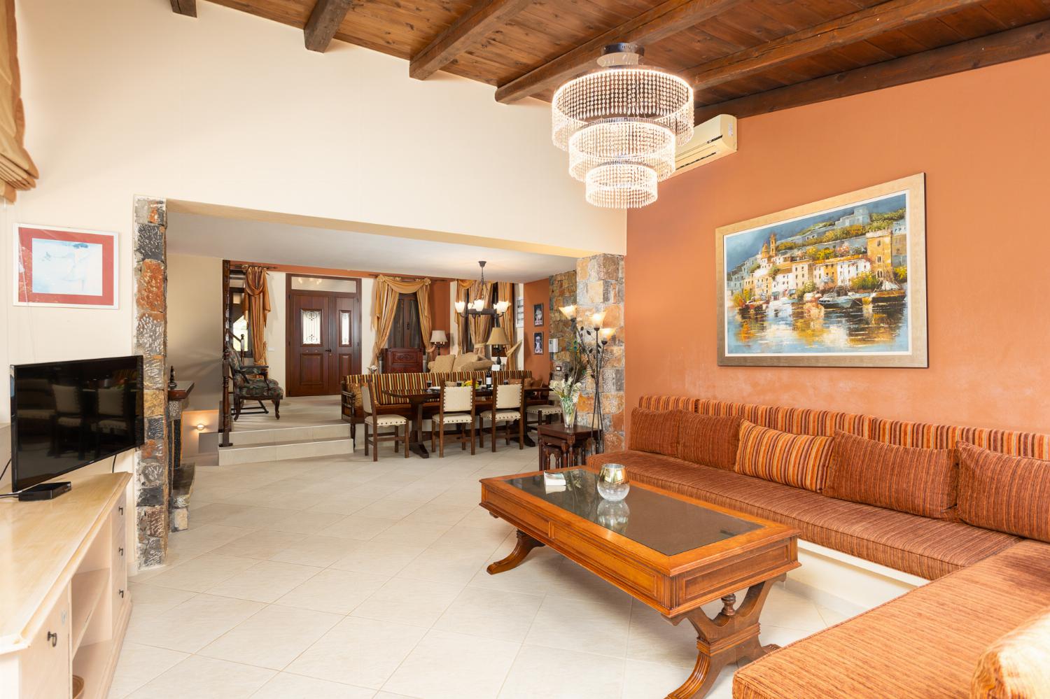 Open-plan living room with sofas, dining area, kitchen, ornamental fireplace, A/C, WiFi internet, and satellite TV