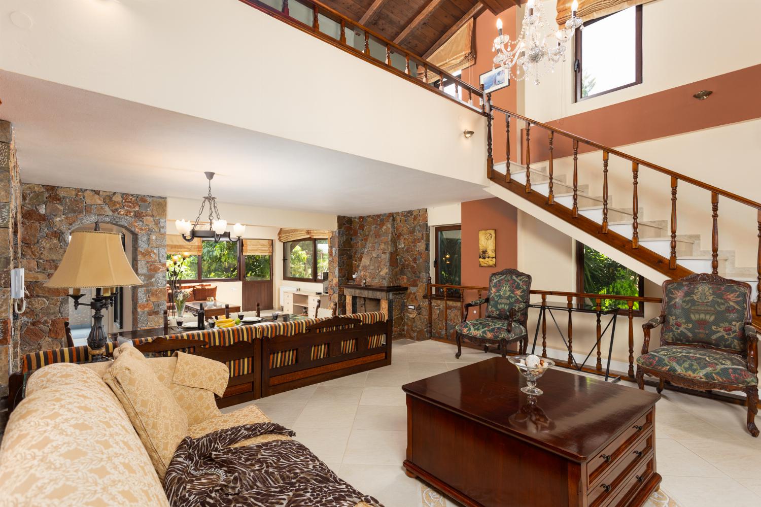 Open-plan living room with sofas, dining area, kitchen, ornamental fireplace, A/C, WiFi internet, and satellite TV