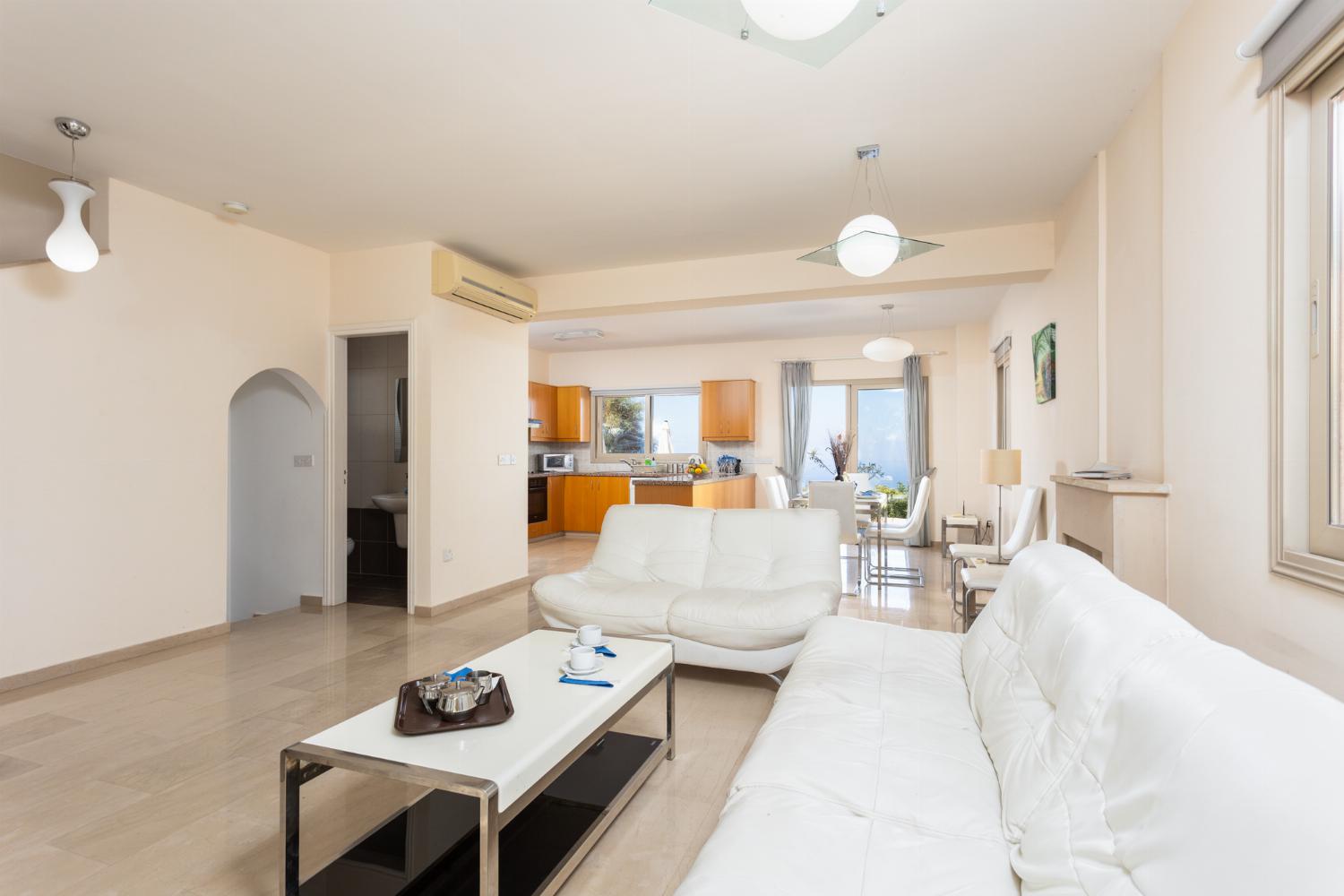 Open-plan living room with sofas, dining area, kitchen, ornamental fireplace, A/C, WiFi internet, and satellite TV