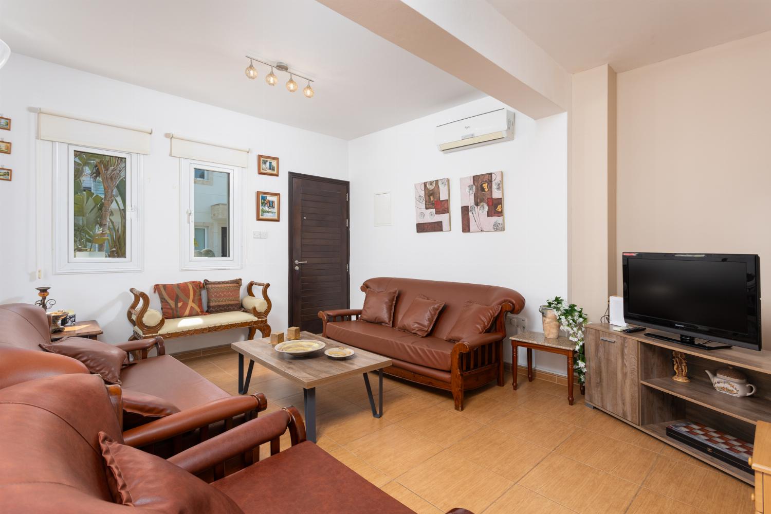 Open-plan living room with sofas, dining area, kitchen, A/C, WiFi internet, and satellite TV