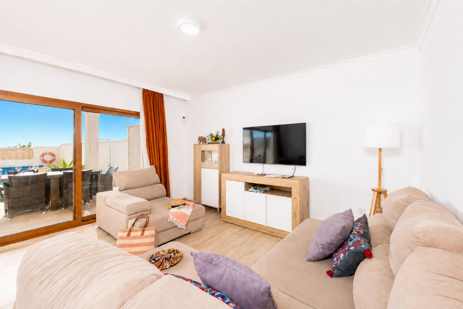 Open-plan living room with sofa, dining area, kitchen, A/C, WiFi internet, and satellite TV
