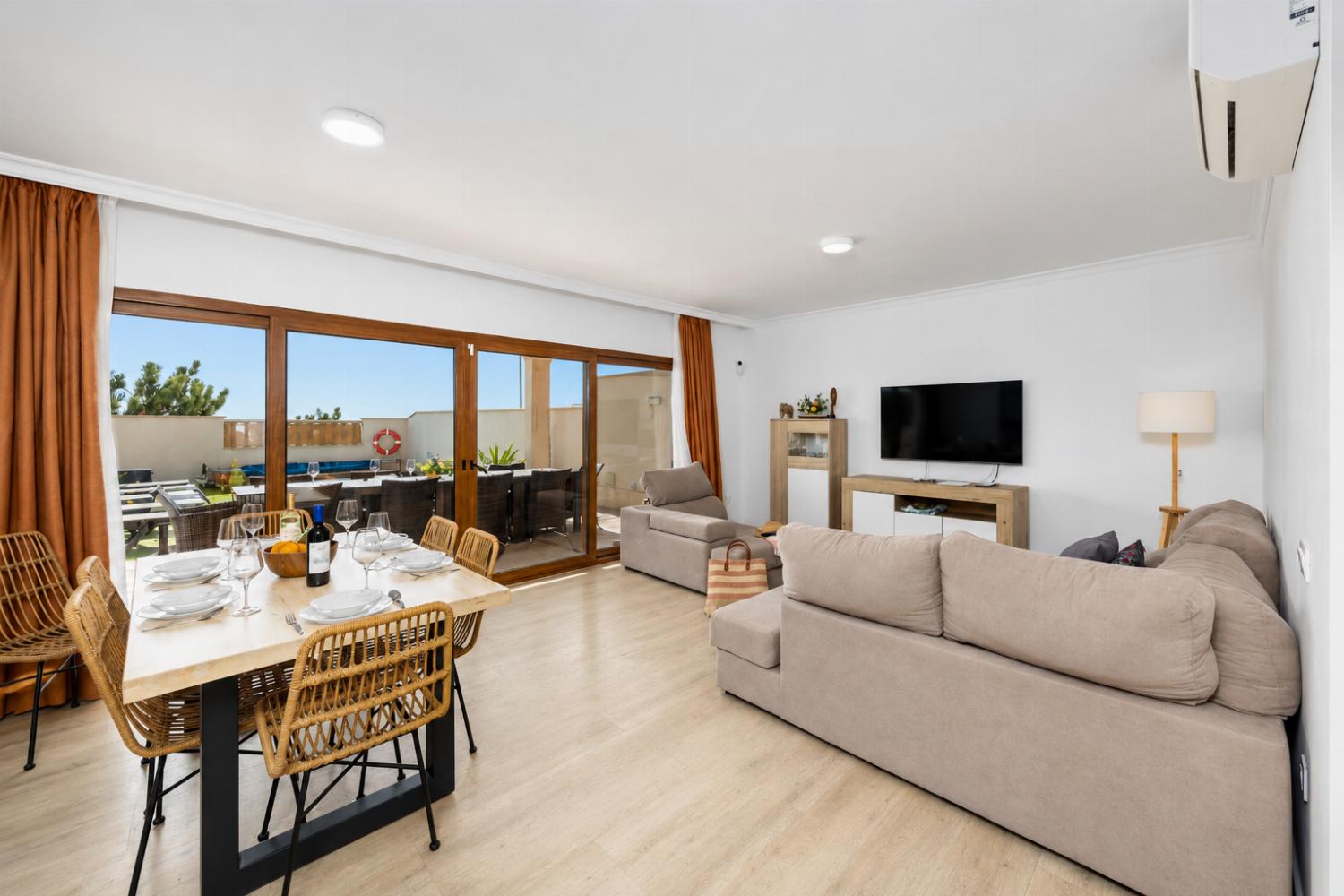 Open-plan living room with sofa, dining area, kitchen, A/C, WiFi internet, and satellite TV