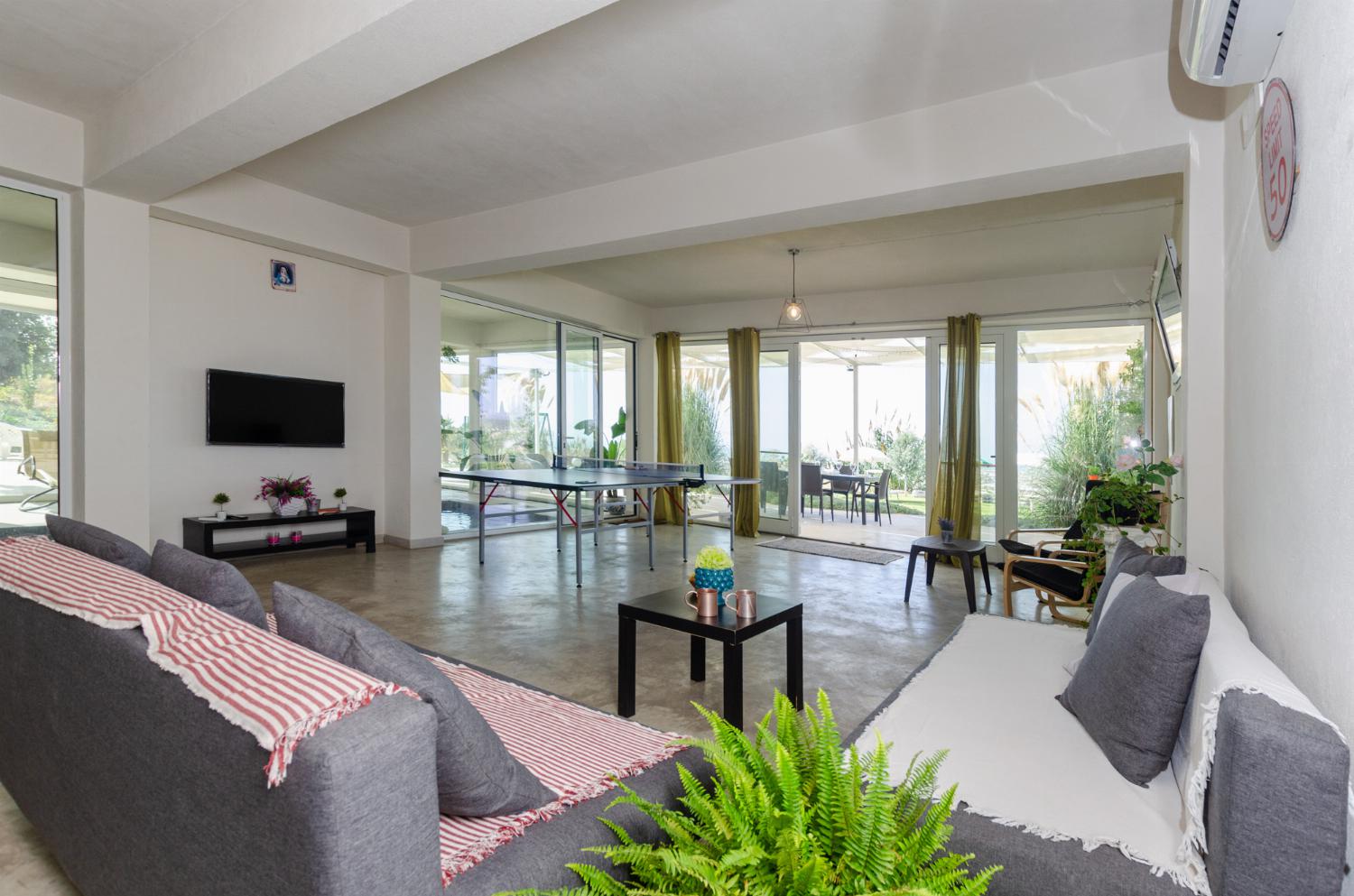 Open plan living room with comfortable sofas, TV, patio doors, AC