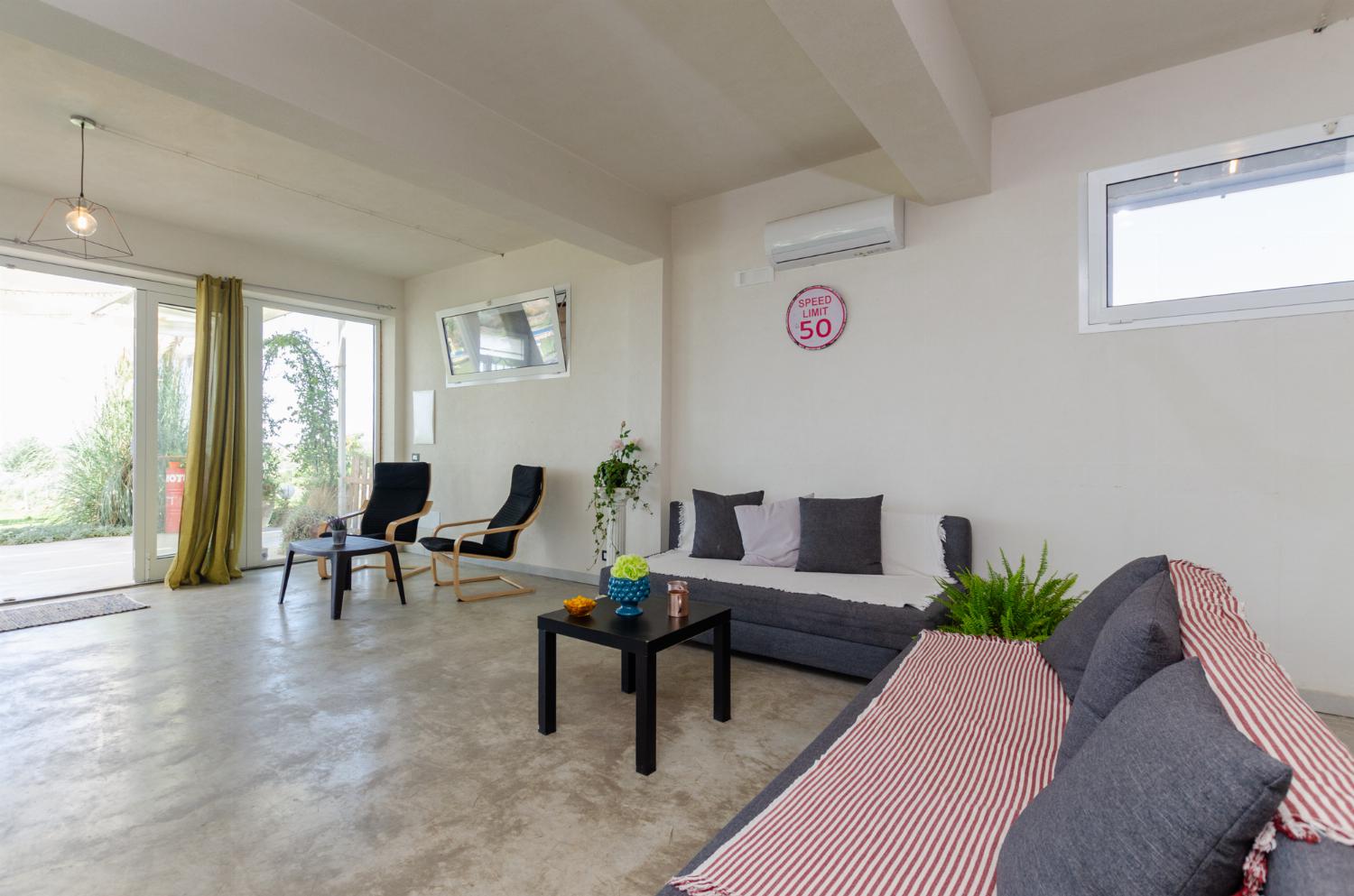 Open plan living room with comfortable sofas, TV, patio doors, AC