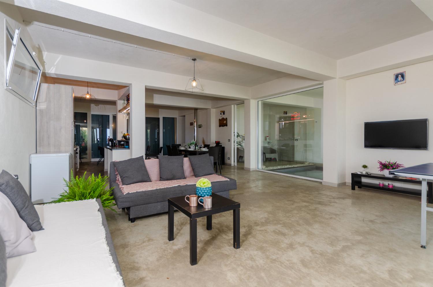 Open plan living room with comfortable sofas, TV, patio doors, AC