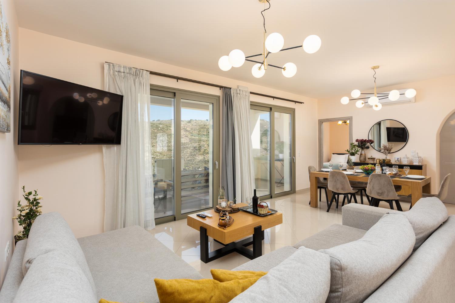 Open-plan living room with sofa, dining area, kitchen, A/C, WiFi internet, and satellite TV