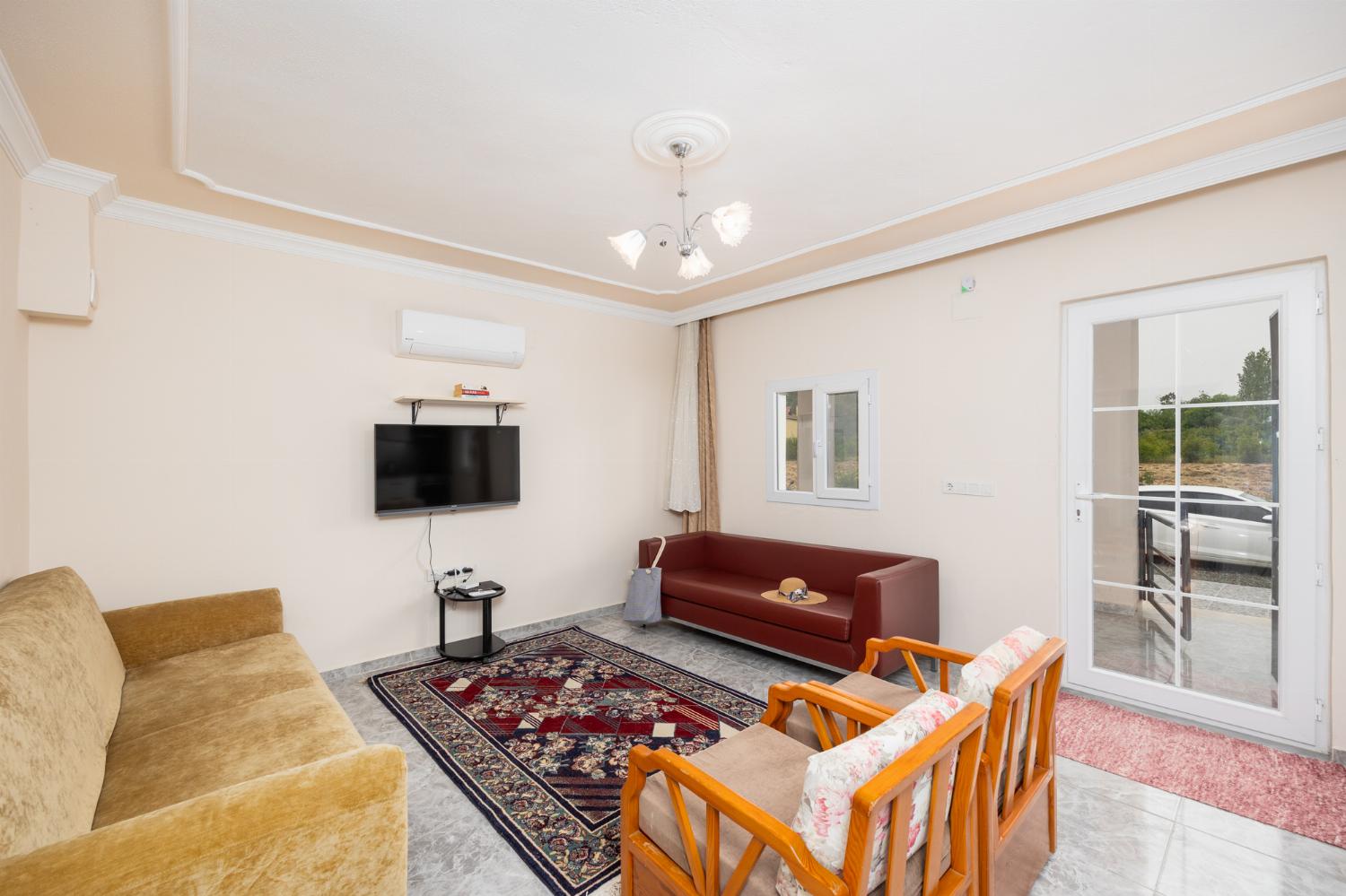 Open-plan living room with sofas, dining area, kitchen, A/C, WiFi internet, and satellite TV