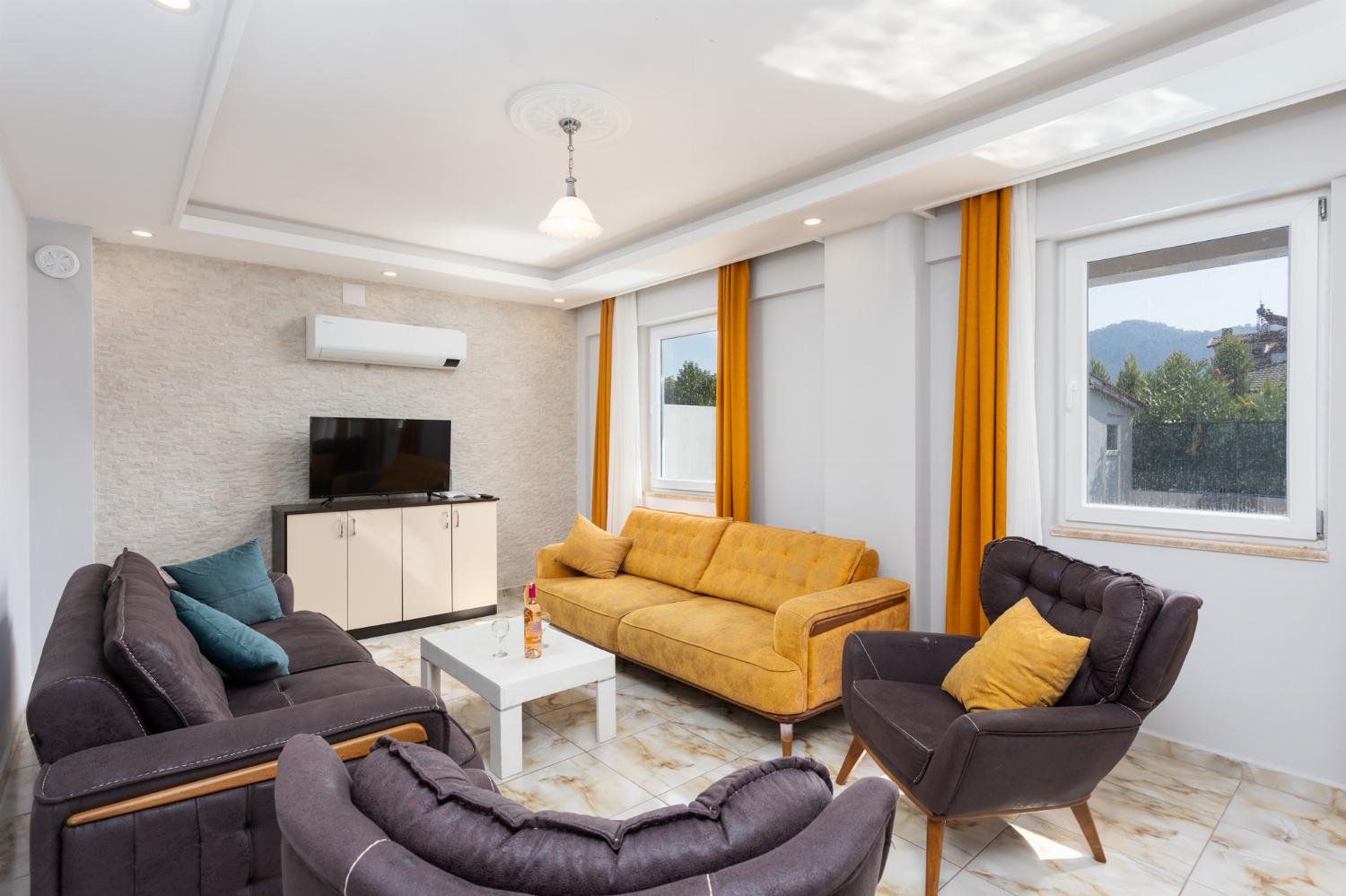 Open-plan living room with sofas, kitchen, A/C, WiFi internet, and satellite TV