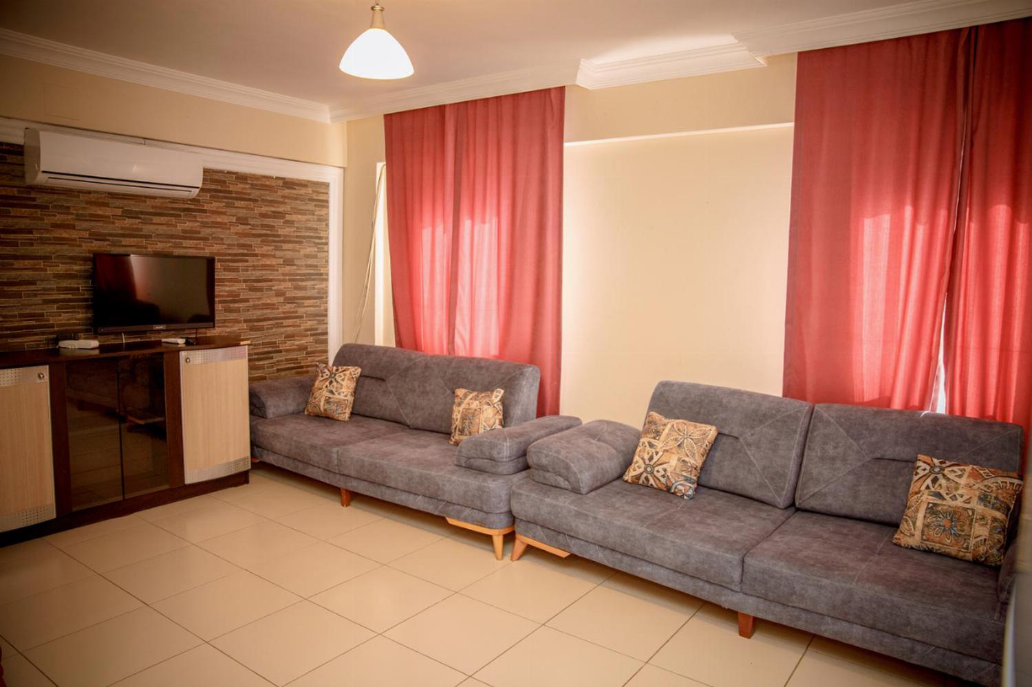 Open-plan living room with sofas, dining area, kitchen, A/C, WiFi internet, satellite TV