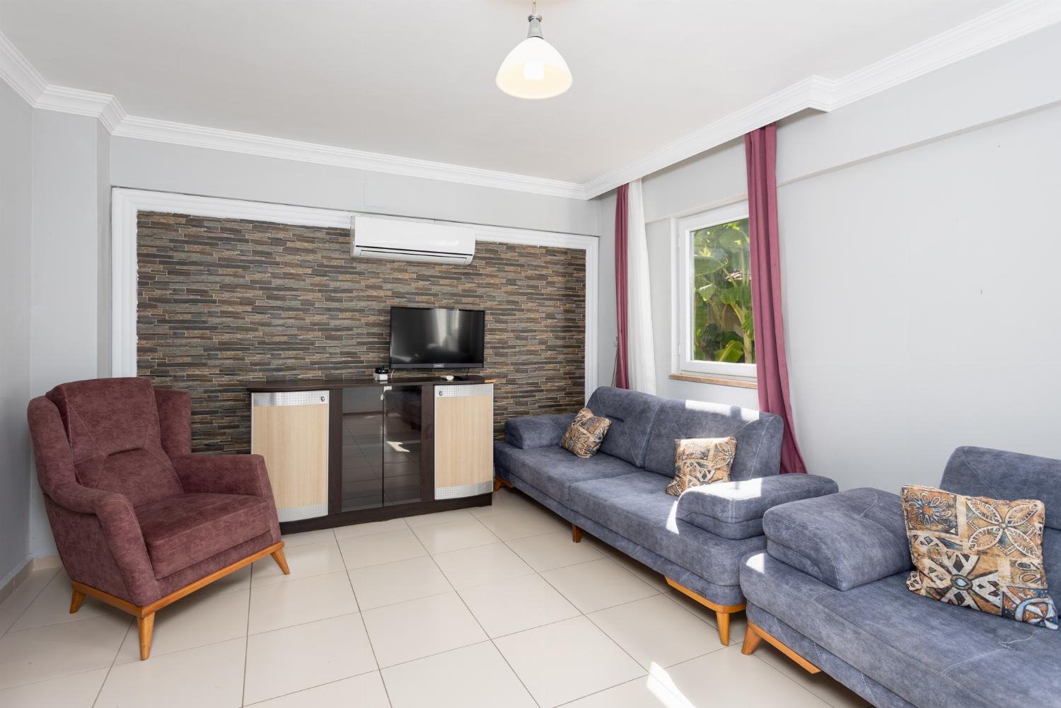 Open-plan living room with sofas, kitchen, A/C, WiFi internet, and satellite TV