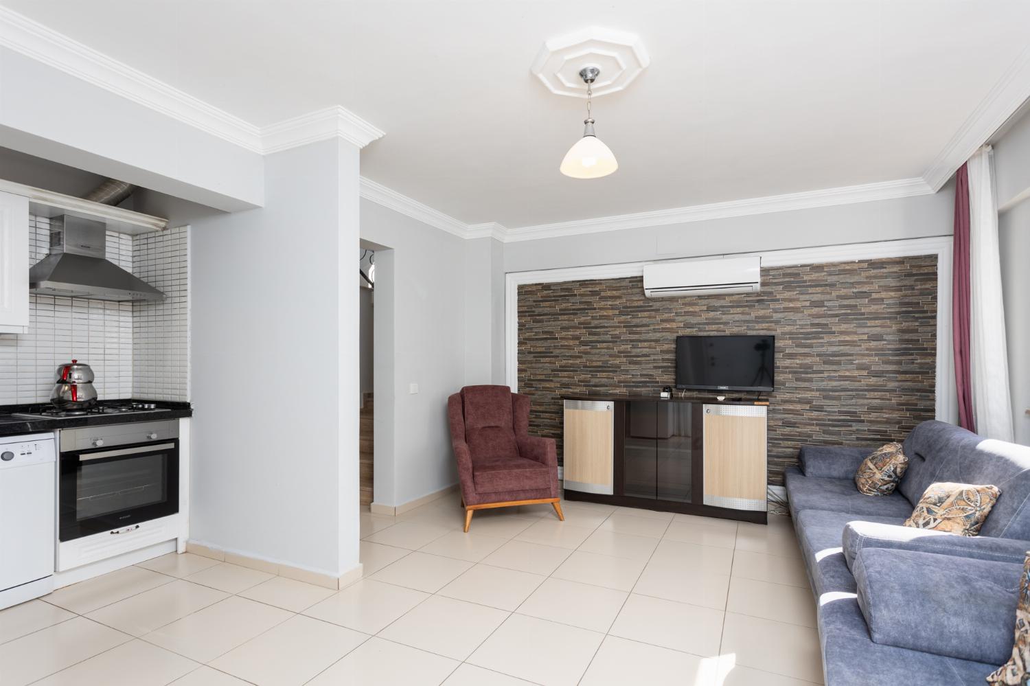 Open-plan living room with sofas, kitchen, A/C, WiFi internet, and satellite TV