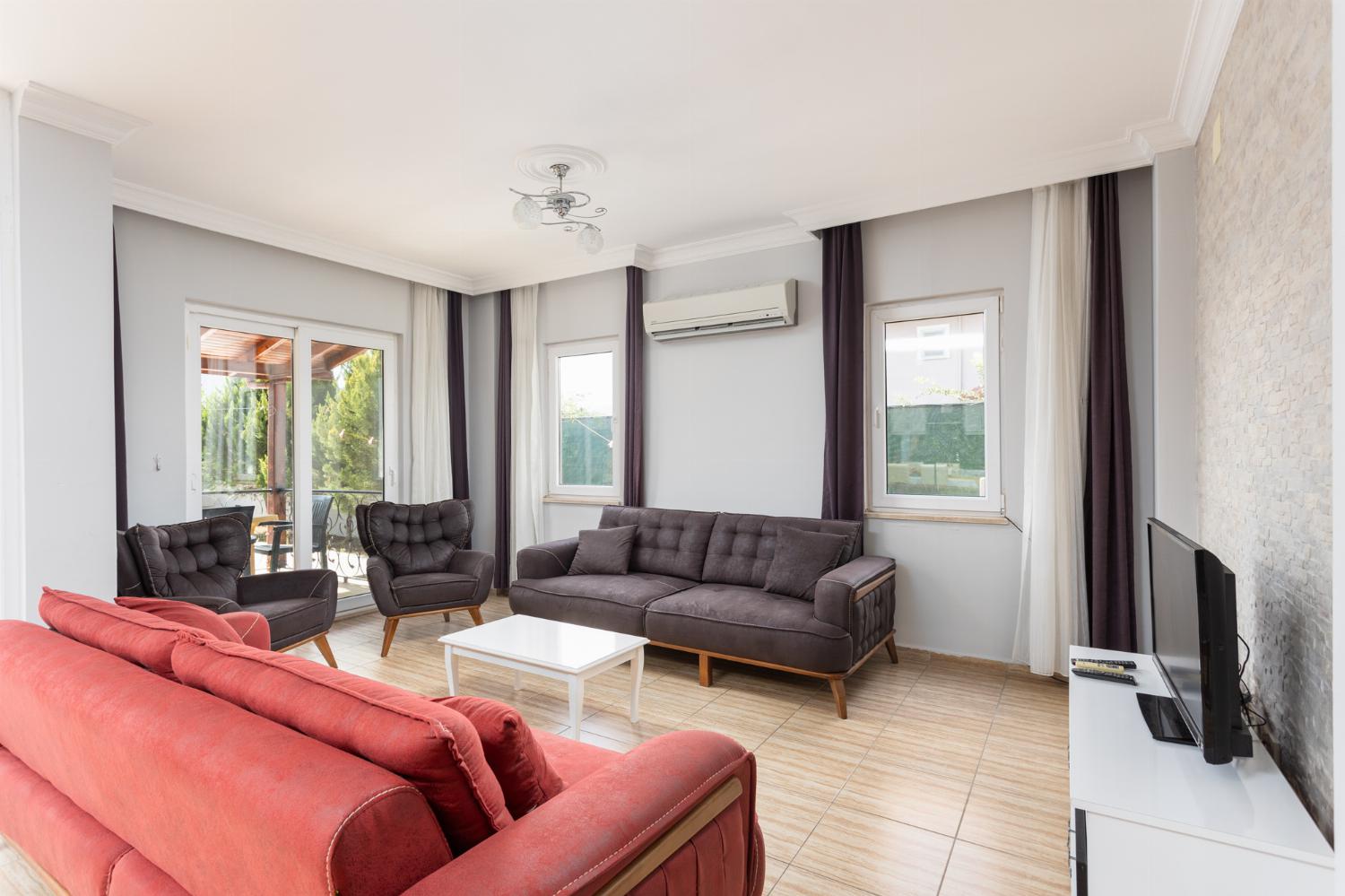Open-plan living room with sofas, dining area, kitchen, A/C, WiFi internet, and satellite TV