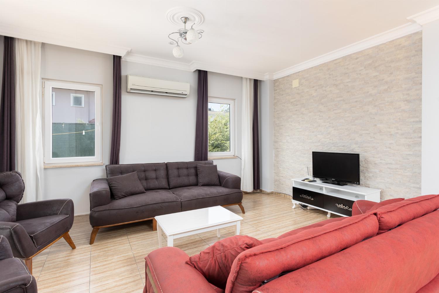 Open-plan living room with sofas, dining area, kitchen, A/C, WiFi internet, and satellite TV