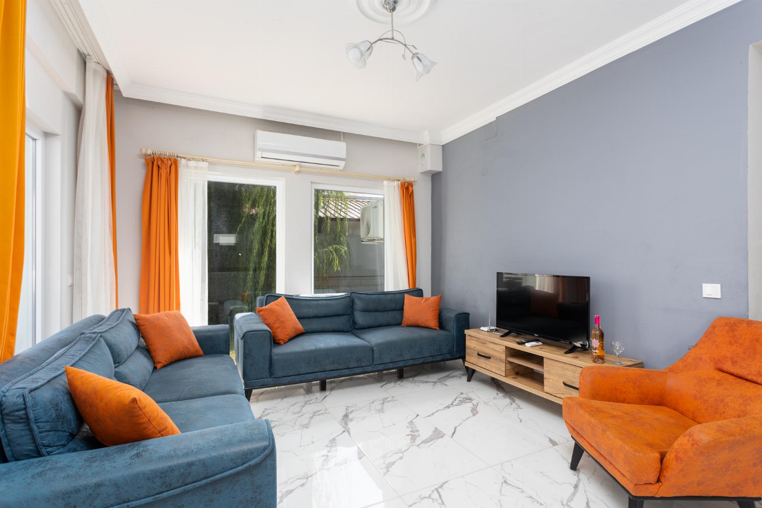Open-plan living room with sofas, kitchen, A/C, WiFi internet, and satellite TV