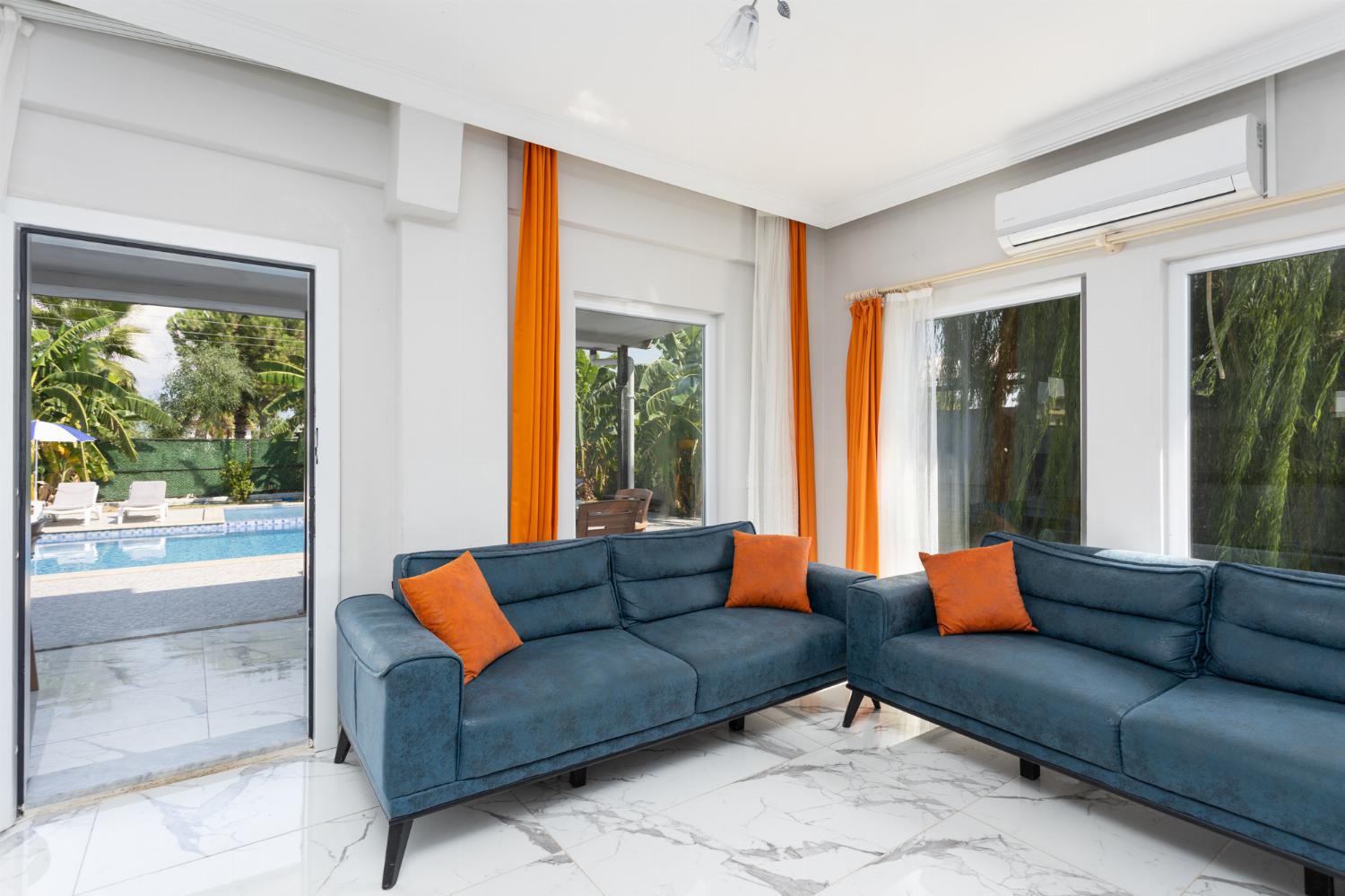 Open-plan living room with sofas, kitchen, A/C, WiFi internet, and satellite TV