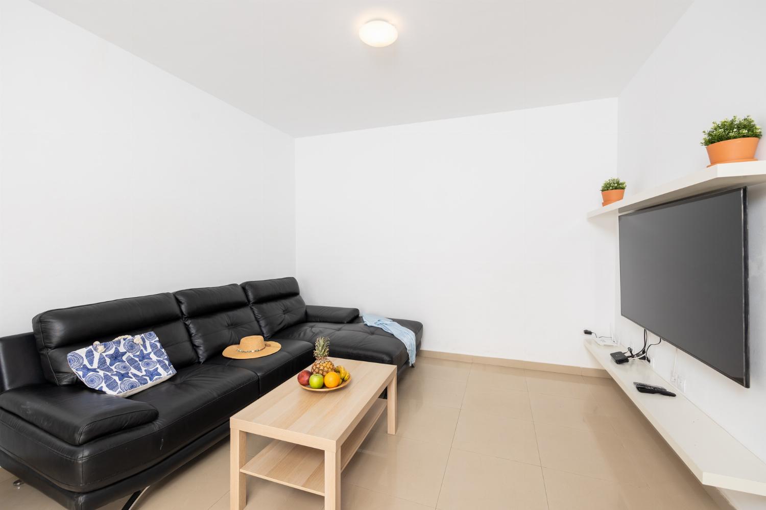 Living room with sofa, dining area, kitchen, and satellite TV