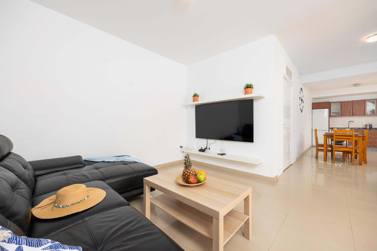 Living room with sofa, dining area, kitchen, and satellite TV