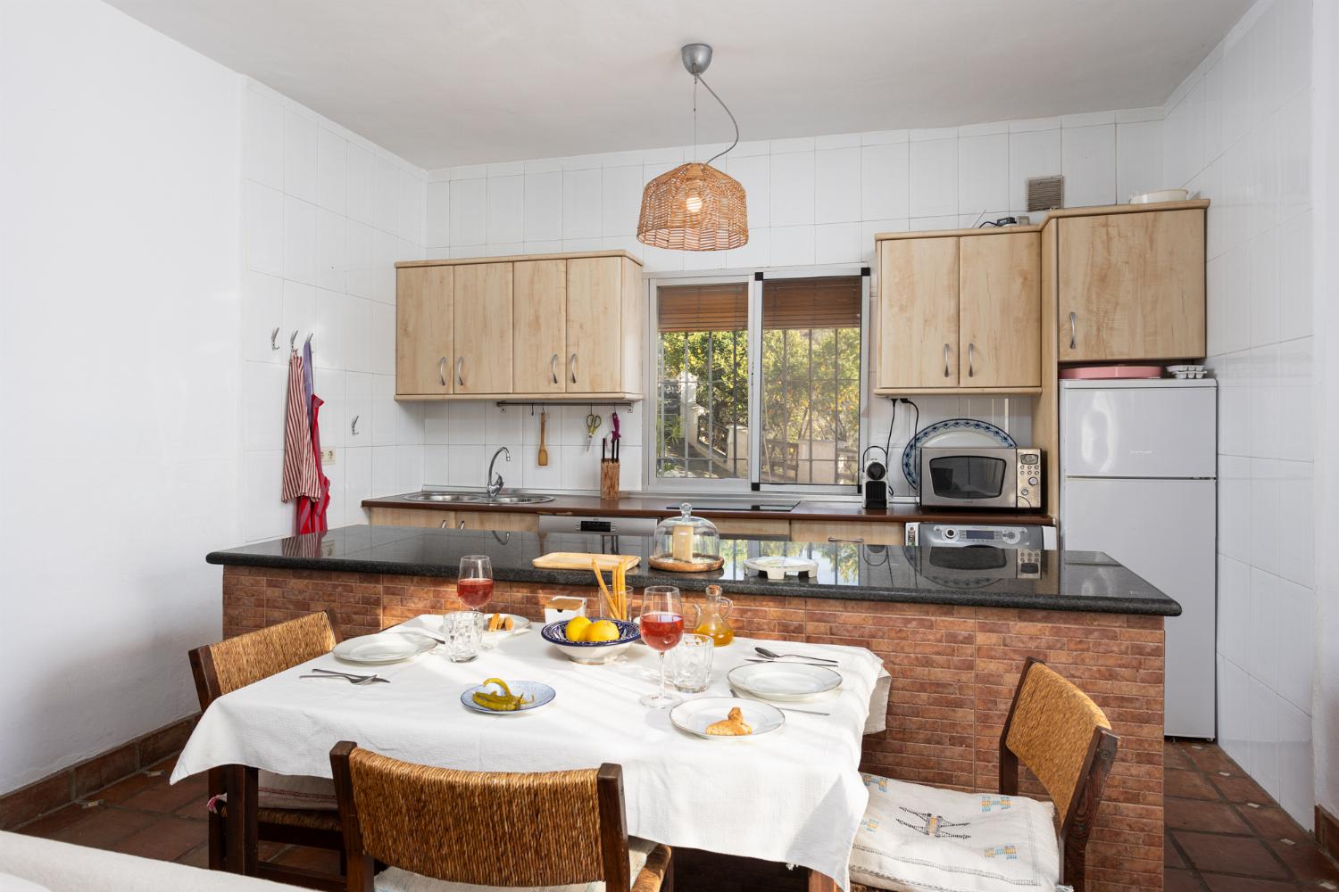 Open-plan living room with sofas, dining area, kitchen, ornamental fireplace, A/C, WiFi internet, and satellite TV