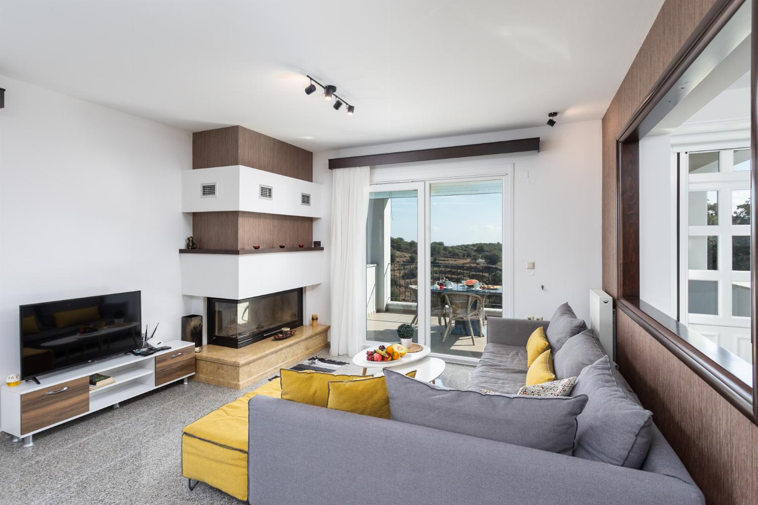 Open-plan living room with sofa, dining area, kitchen, ornamental fireplace, WiFi internet, satellite TV, and sea views